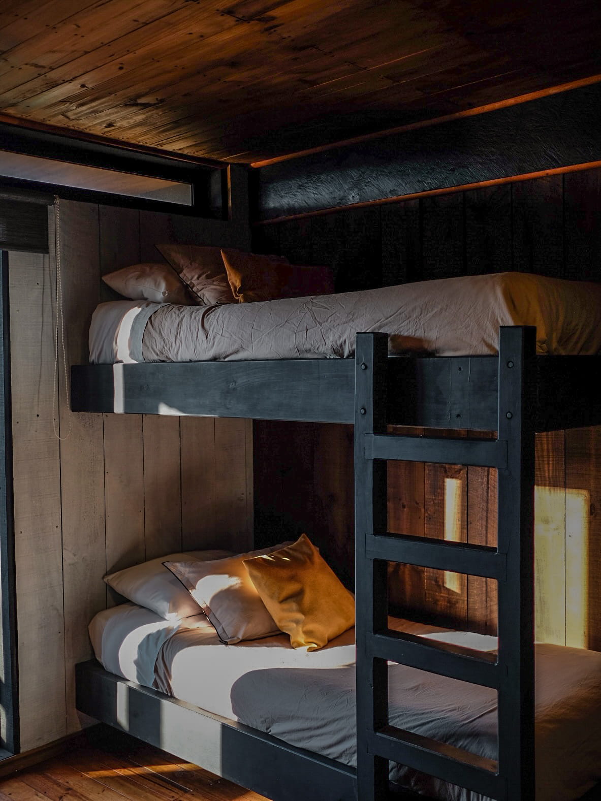 Camarote de madera negra con ropa de cama cálida