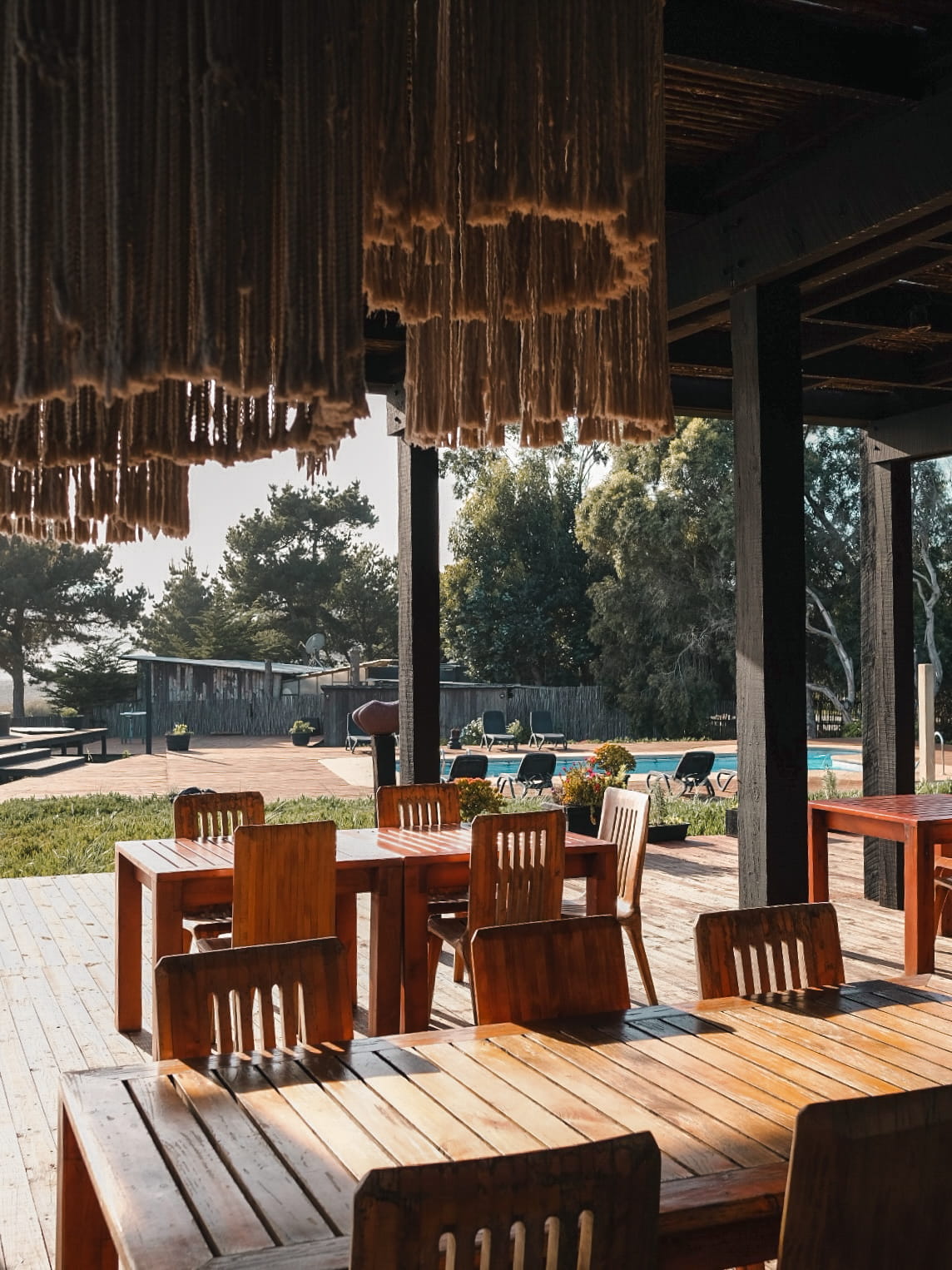 Terraza con mesas de madera junto a la piscina